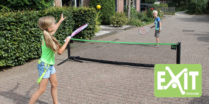 Zwei Kinder spielen draußen auf dem Hof Tennis mit Schlägern und weichem Ball über ein EXIT Multi-Sport Net.