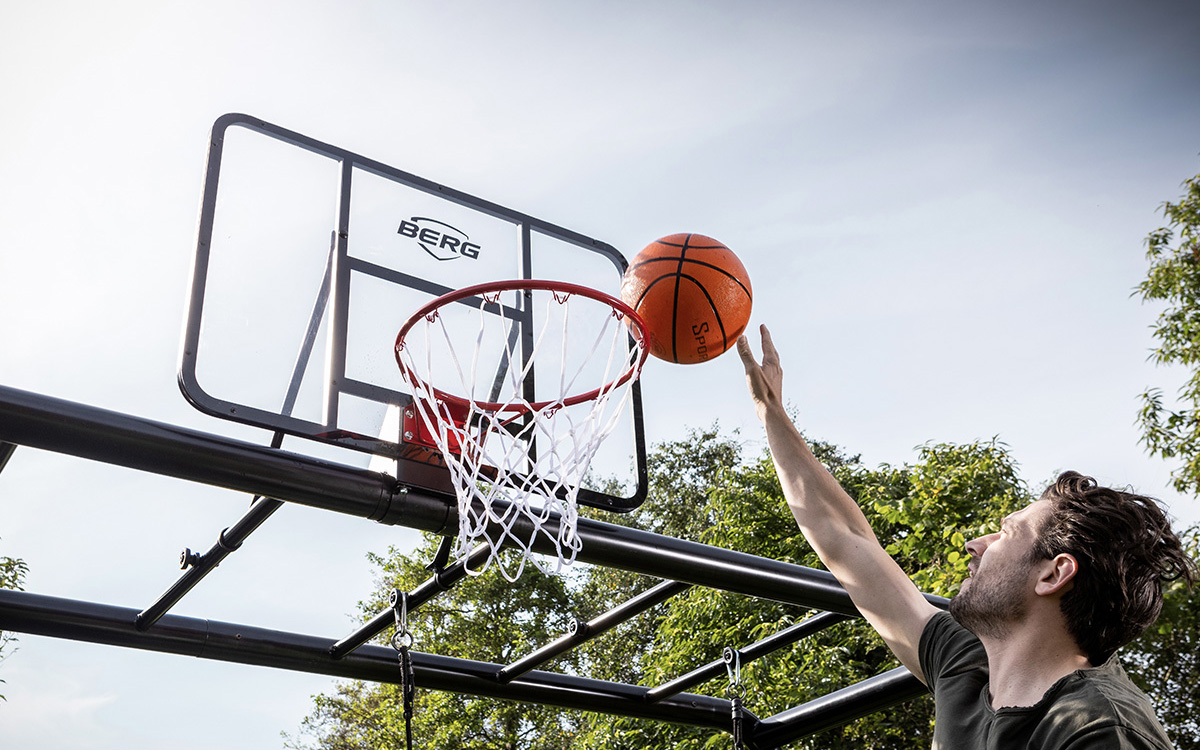 Ein Mann wirft einen Basketball in den Basketballkorb, der an der PlayBase montiert ist.