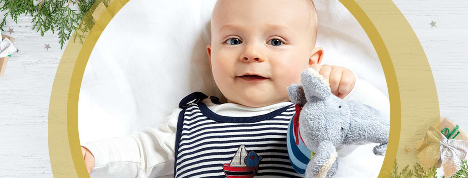 Ein Baby hält sein Lieblingskuscheltier in der Hand und lächelt dabei.
