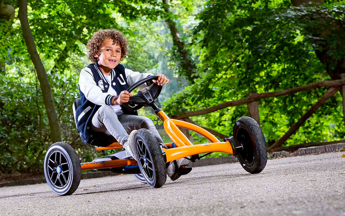 Ein Junge fährt mit dem BERG Buddy B-Orange 2.0 Gokart auf einem Weg durch die Natur.