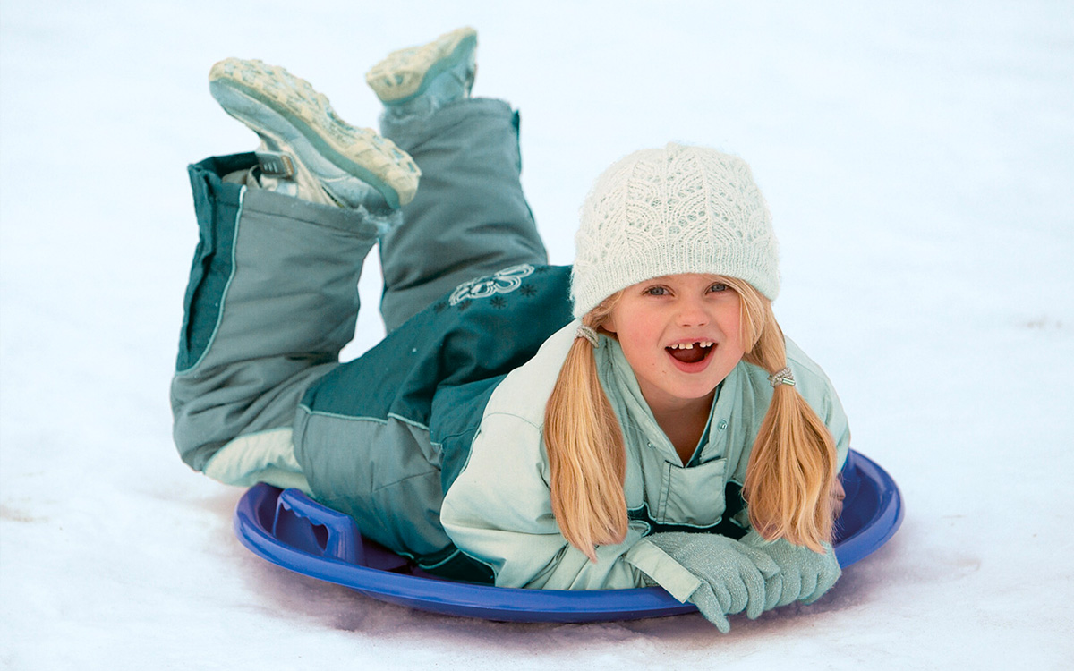 Ein Mädchen fährt mt dem Fun-Bob von dantoy den Schneehang hinunter.