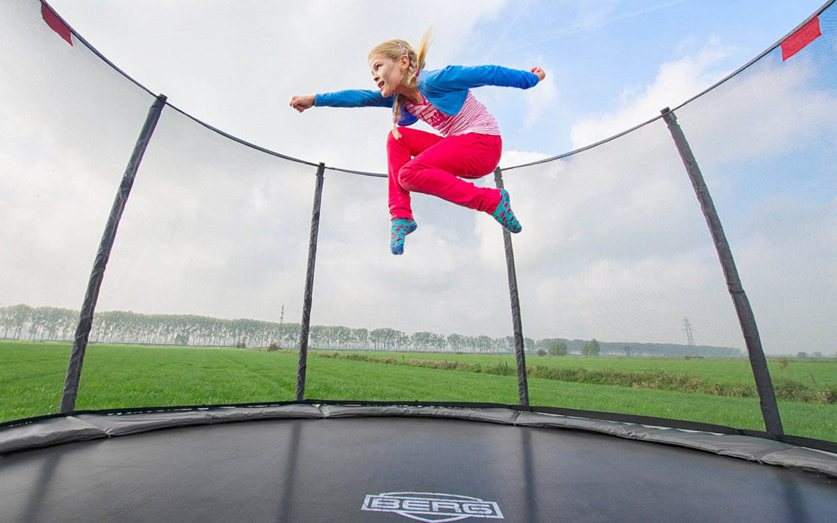 Ein Mädchen springt auf einem BERG Trampolin hoch und macht akrobatische Posen.